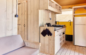 Interno della tenda safari Outback al campeggio Spina Family Collection in Italia con cucina e divano.