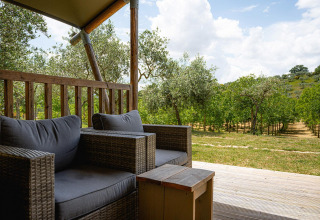 Zicht vanop safari tent Villatent Nomad op Camping Pian Di Boccio in Italië met zetels en groene bomen.