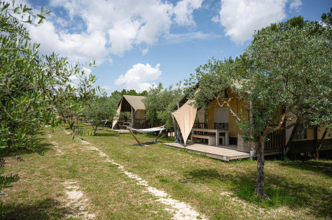 Safaritenten bij Villatent Nomad, Camping Pian Di Boccio in Italië, omringd door bomen en hangmatten.