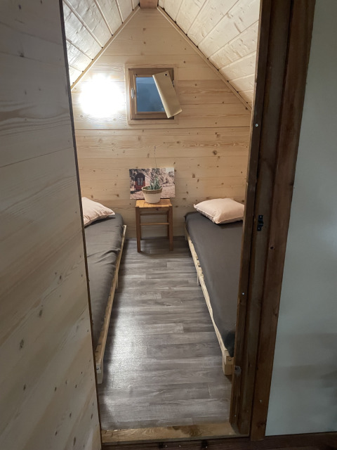 Kleine slaapkamer in safaritent met twee eenpersoonsbedden en houten muren op Camping Des Randonneurs in Frankrijk.