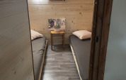 Piccola camera nel bivacco safari con due letti singoli e pareti in legno al Camping Des Randonneurs, Francia.