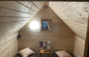 Cozy cabin room with two single beds, wooden walls, small window and light, in a French safari tent.