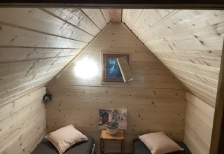 Knusse kamer met twee eenpersoonsbedden, houten wanden en raam, in een Franse safaritent.