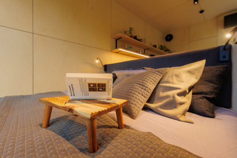 Knus bed met kussens, houten dienblad en boek in River Mirrorlodge, Holiday park Mölke, Nederland.