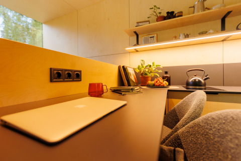 Moderne werkruimte met laptop, rode beker en planten in River Mirrorlodge, Holiday park Mölke, Nederland.