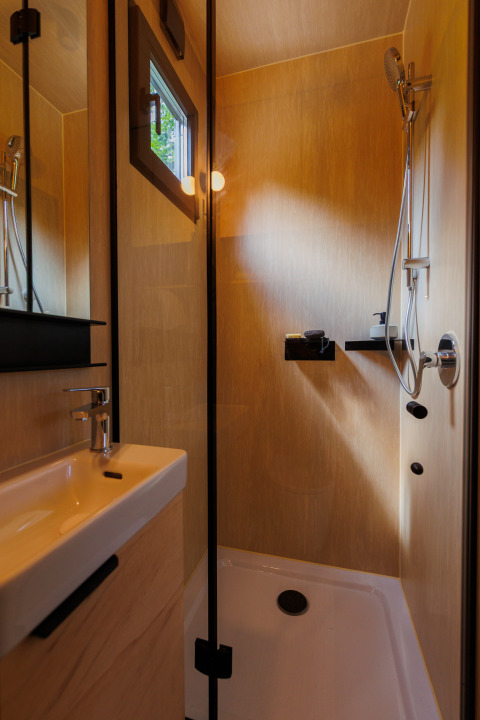 Moderne compacte badkamer met douche en wastafel in River Mirrorlodge van Holiday park Mölke in Nederland.