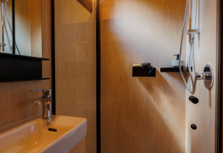 Moderne compacte badkamer met douche en wastafel in River Mirrorlodge van Holiday park Mölke in Nederland.