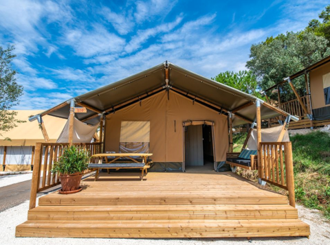 Safari tent Lodge tent Bergerac Deluxe with wooden deck, picnic table, and bench under a clear blue sky.