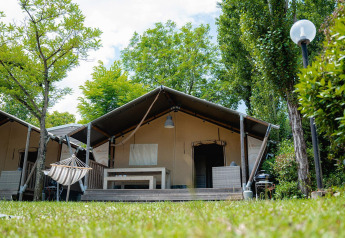 Tenda safari Villatent Wood al Camping Il Poggetto in Italia, immersa nel verde tra alberi e prato.