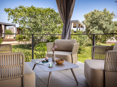 Gezellige terras met moderne tuinmeubels en zicht op tuin bij Premium Holiday Home, Aminess Planet Camping Sirena, Kroatië.