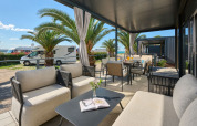 Casa vacanze di lusso con terrazza coperta, arredi moderni e palme al camping Aminess Planet Sirena, Croazia.