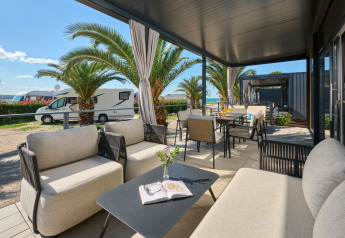 Terraza cubierta de casa de lujo con muebles modernos y palmeras en Aminess Planet Camping Sirena, Croacia.