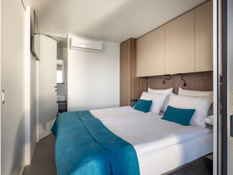 Lichte moderne slaapkamer met tweepersoonsbed en turquoise accenten in een luxe vakantiewoning in Kroatië.