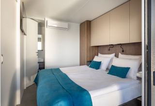 Lichte moderne slaapkamer met tweepersoonsbed en turquoise accenten in een luxe vakantiewoning in Kroatië.