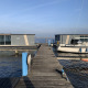Foto della houseboat «Havenlodge» alla Marina Uitgeest nei Paesi Bassi, con barche e pontile di legno.