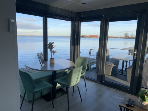 Eethoek in houseboat ‘Havenlodge Plus’ aan Marina Uitgeest, Nederland, met zicht op het water.