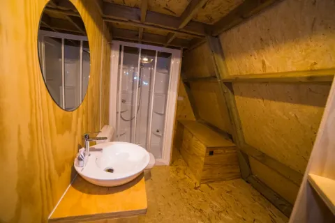 Badkamer met houten vloer, wastafel, spiegel en douche bij A Luxury lodge in Chianti Glamping Resort, Italië.