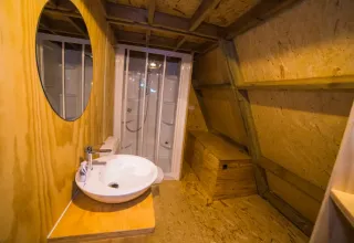 Badkamer met houten vloer, wastafel, spiegel en douche bij A Luxury lodge in Chianti Glamping Resort, Italië.