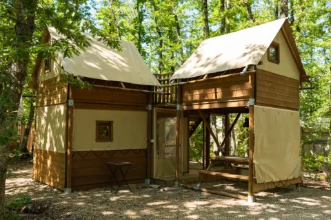Safari-Zelt Air Dreamer 2 im Chianti Glamping Resort, Italien, umgeben von grünen Bäumen im Wald.