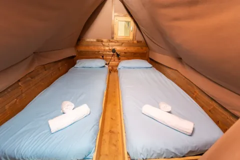 Zwei Einzelbetten mit hellblauer Bettwäsche im Safari-Zelt ‚Air Dreamer‘ 3 im Chianti Glamping Resort, Italien.