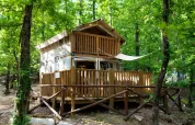 Airlodge 1 im Chianti Glamping Resort, Italien, eine gemütliche Holzhütte umgeben von grünem Wald.