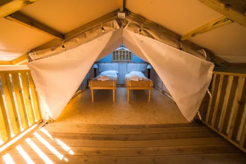 Binnenzicht van Airlodge 2.0 in Chianti Glamping Resort, Italië, met twee aparte bedden en houten vloer.