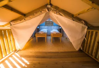 Binnenzicht van Airlodge 2.0 in Chianti Glamping Resort, Italië, met twee aparte bedden en houten vloer.