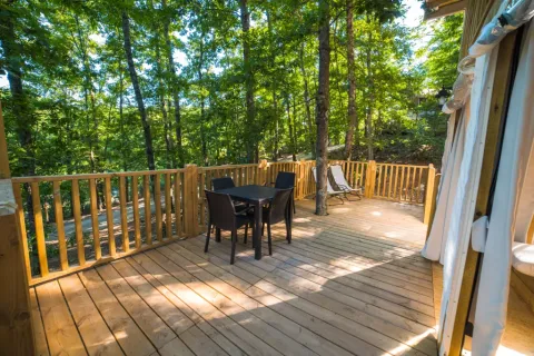 Houten terras bij Airlodge 2.0 in Chianti Glamping Resort, Italië, met tafel, stoelen en boszicht.