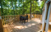 Holzterrasse der Airlodge 2.0 im Chianti Glamping Resort Italien mit Sitzbereich und Blick auf Bäume.