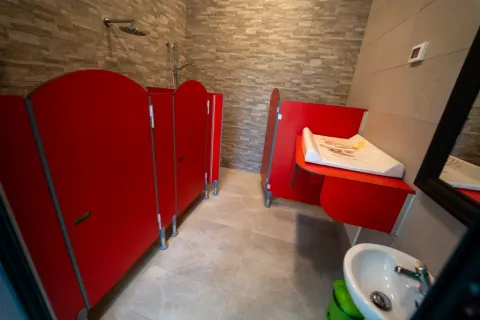 Salle de bain pour enfants dans une tente safari avec cabines rouges, table à langer et lavabo.