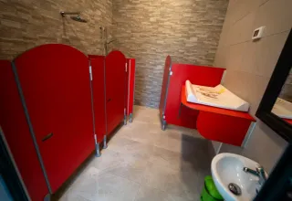Salle de bain pour enfants dans une tente safari avec cabines rouges, table à langer et lavabo.