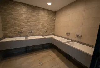 Espace de lavage commun moderne avec plusieurs lavabos et robinets dans une tente safari.