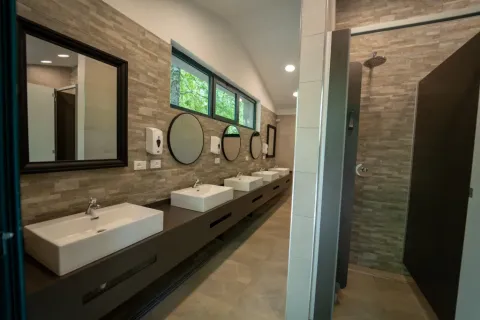 Salle de bains moderne dans une tente safari, avec lavabos, miroirs et une grande douche confortable.