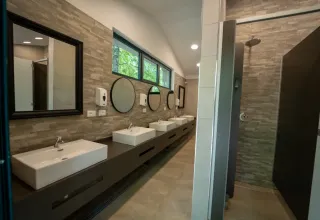Salle de bains moderne dans une tente safari, avec lavabos, miroirs et une grande douche confortable.