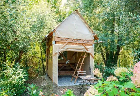 Tente safari appelée « Airstay » au Chianti Glamping Resort en Italie, entourée de végétation luxuriante.