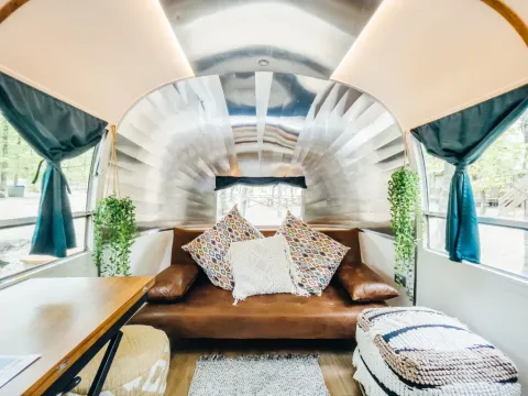 Interieur van een kleine Airstream-woning bij Chianti Glamping Resort in Italië met knusse bank en planten.