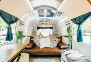 Interieur van een kleine Airstream-woning bij Chianti Glamping Resort in Italië met knusse bank en planten.