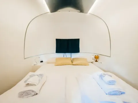 Gezellige slaapkamer in de Airstream tiny house bij Chianti Glamping Resort, Italië, met frisse witte lakens.