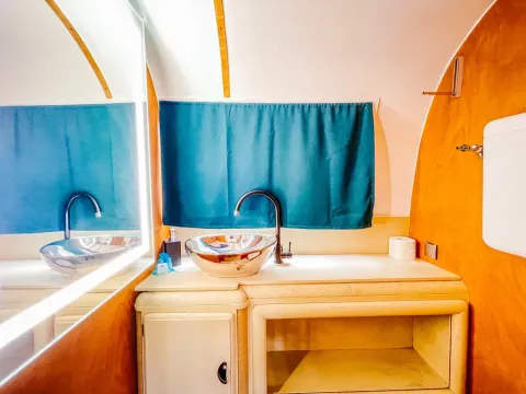 Modern badkamermeubel in Airstream tiny house bij Chianti Glamping Resort, Italië, met blauwe gordijnen.