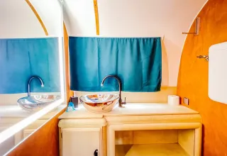 Modern badkamermeubel in Airstream tiny house bij Chianti Glamping Resort, Italië, met blauwe gordijnen.