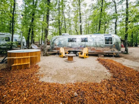 Glimmende Airstream tiny house en houten stoelen met jacuzzi in het bos bij Chianti Glamping Resort, Italië.