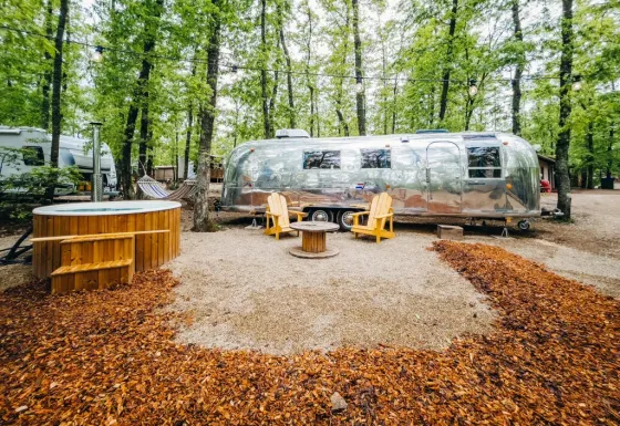 Glimmende Airstream tiny house en houten stoelen met jacuzzi in het bos bij Chianti Glamping Resort, Italië.