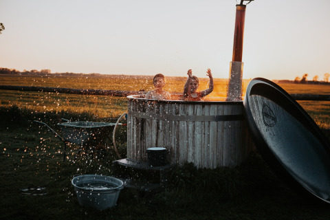 Kinder planschen in einer Außentonne bei Sonnenuntergang auf dem BoerenBed Ferme de Vanadal, Occitanie, Frankreich.
