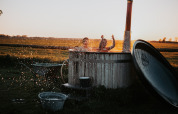 Børn leger i et udendørs karbad med vandstænk ved solnedgang på BoerenBed Ferme de Vanadal, Occitanie, Frankrig.