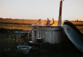 Children splashing and playing in an outdoor hot tub at sunset at BoerenBed Ferme de Vanadal, Occitanie, France.