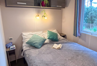Bedroom at Mobile Home Comfort in Campsite Demoiselles Plage, France, featuring a double bed and window.