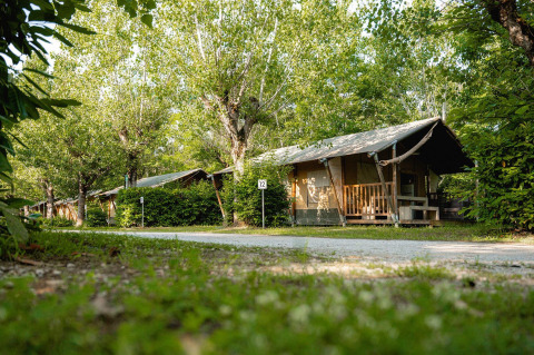Safari-Zelt Villatent Nomad auf Camping La Chiocciola in Italien, umgeben von grünen Bäumen.