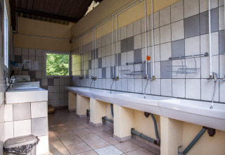 Gemeinschaftswaschraum mit Waschbecken und gefliesten Wänden im Safarizelt auf Camping Les Bouleaux, Frankreich.