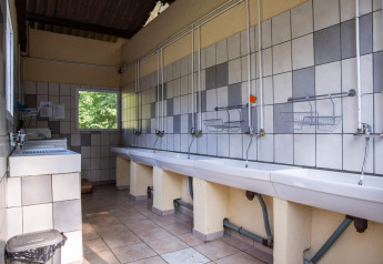 Shared washroom with sinks and tiled walls at the Safari tent at Campsite Les Bouleaux in France.