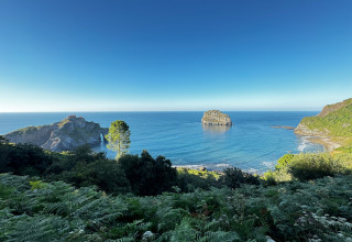 Küstenblick mit Insel und Klippe im Wecamp Cudillero Ferienpark in Asturien, Spanien, an einem klaren Tag.